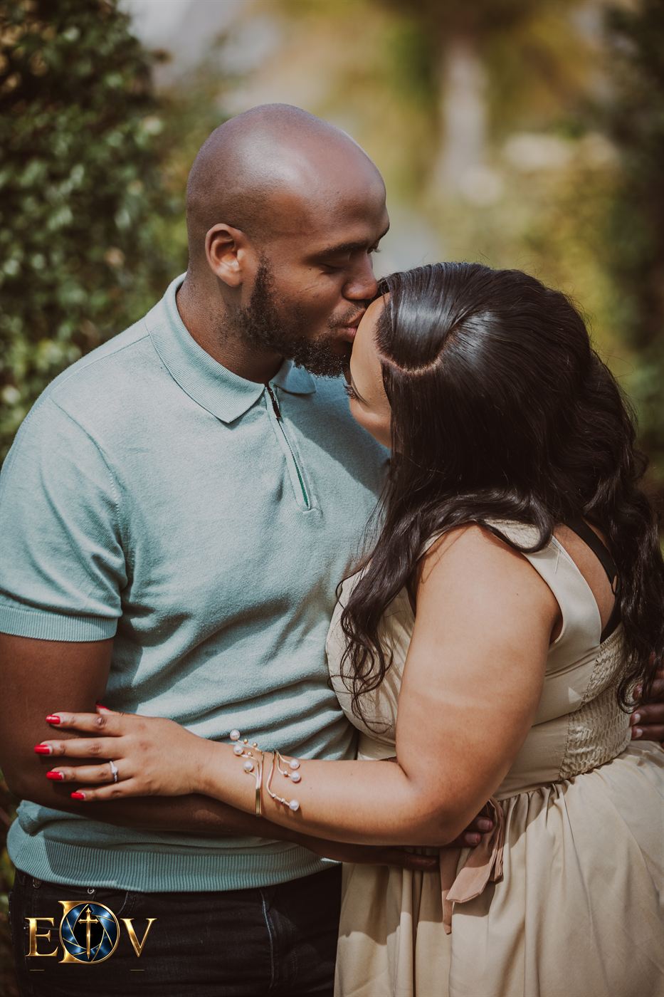 Man kissing his partner's forehead in a garden