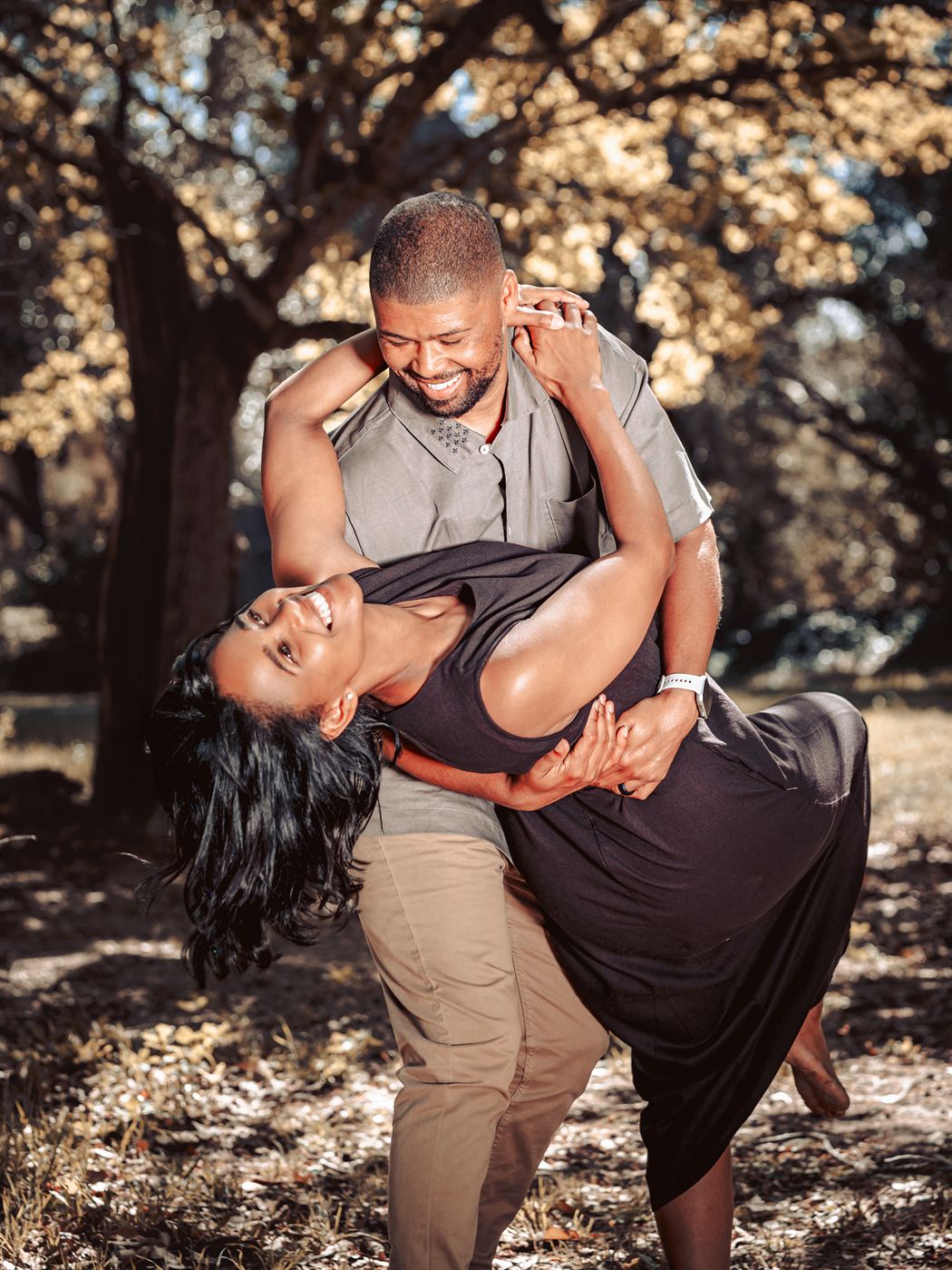 Couple caught mid-dance dip beneath dappled trees