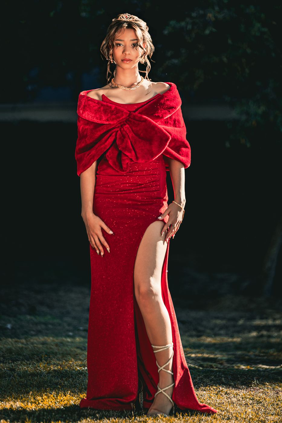 Matric farewell portrait — young woman in a red velvet gown and tiara at dusk
