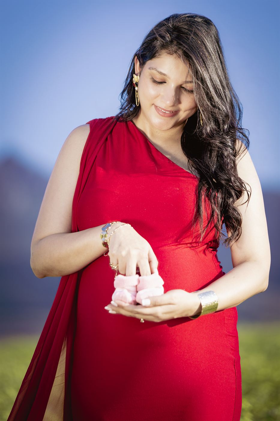 Expectant mother looking down at a pair of tiny pink booties in her hands