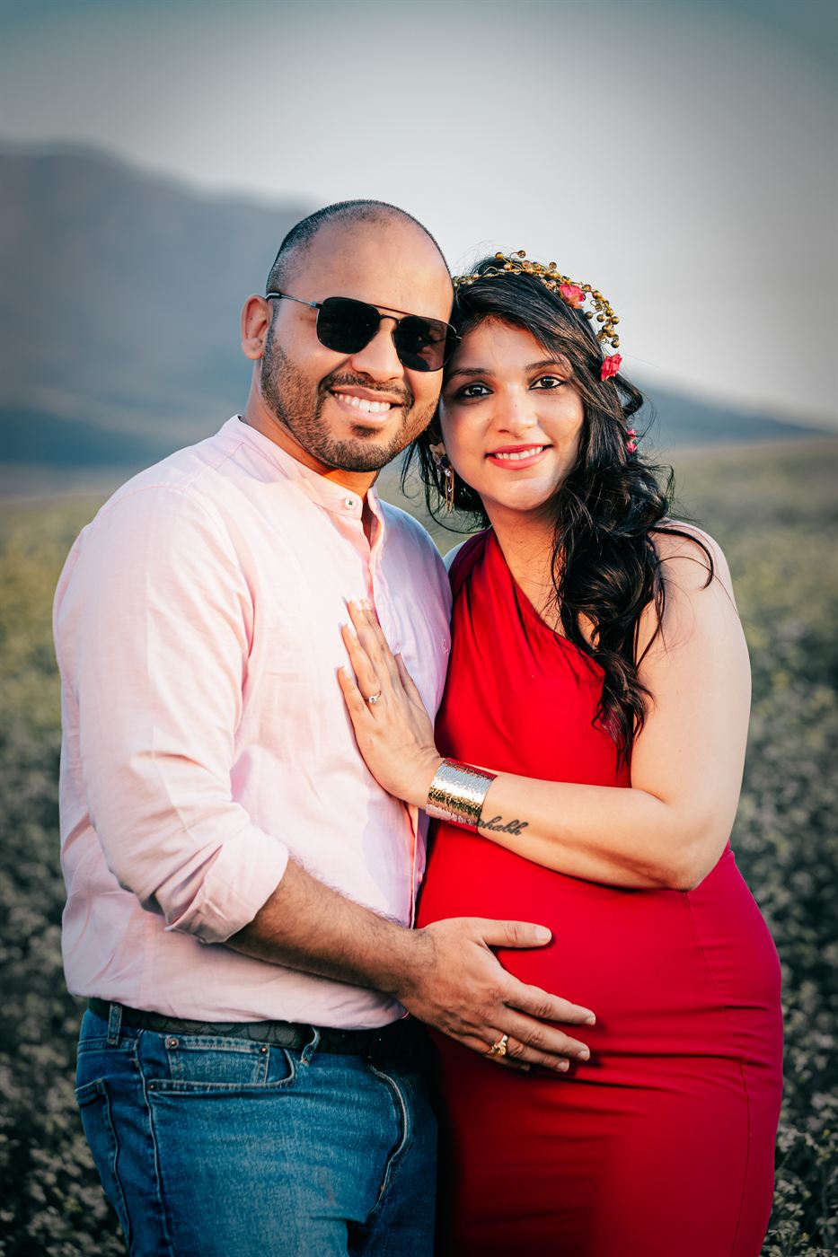 Expectant parents standing together, both hands resting on the bump