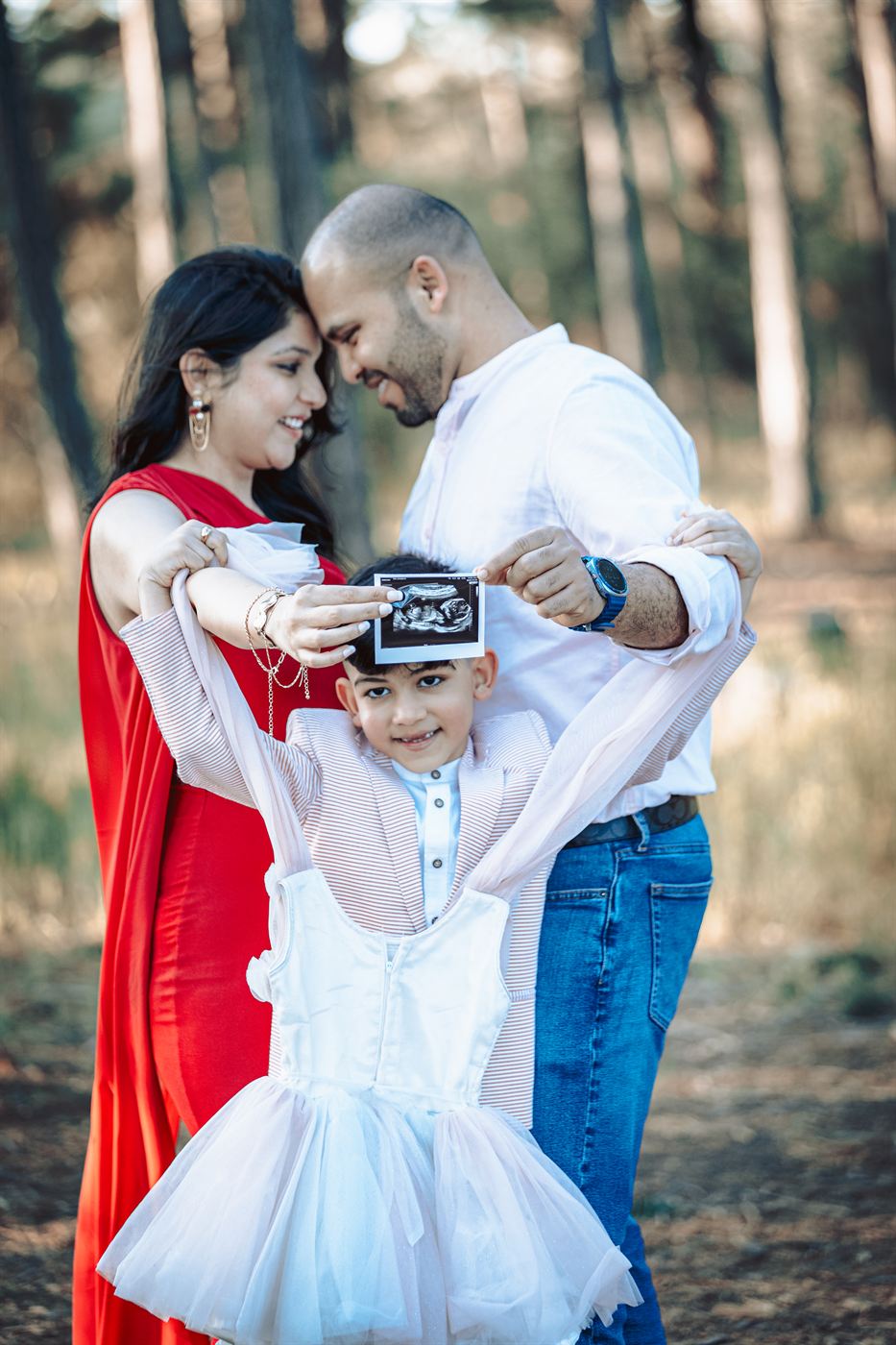 Family of four sharing an ultrasound scan among pine trees
